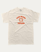 God Bless Taxas graphic tee with bold and humorous print, funny and trendy graphic. Perfect for adults and gift-giving. Cream shirt.