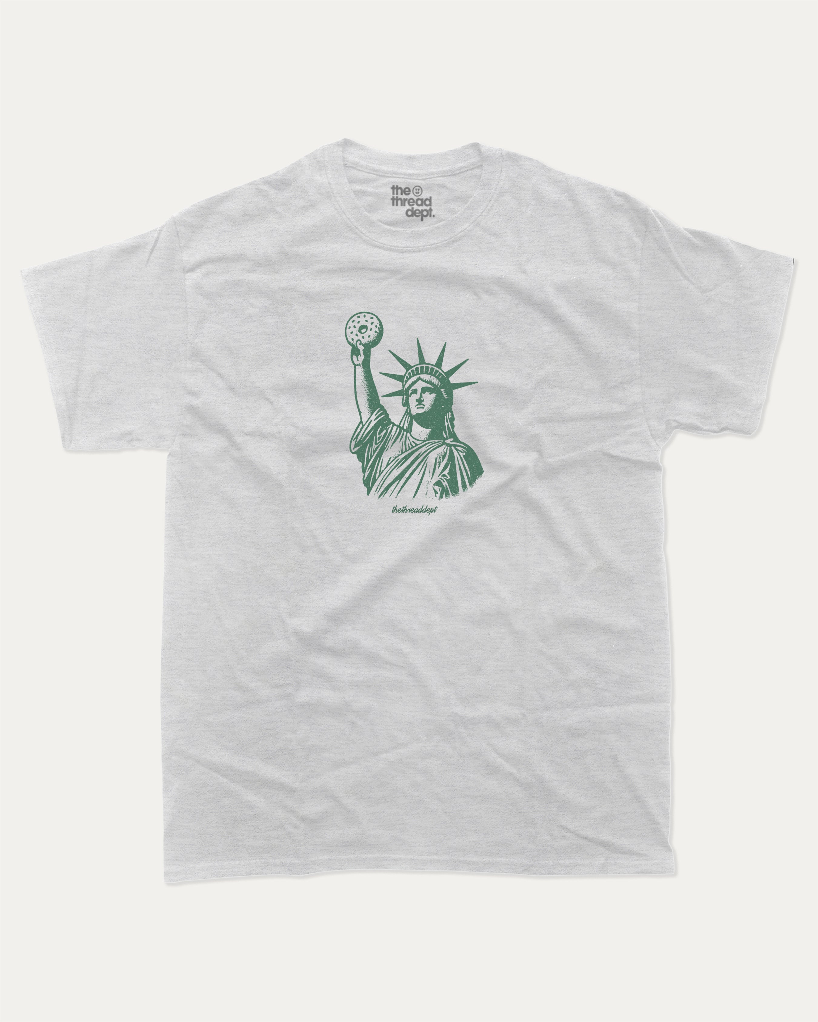 Statue of Liberty Bagle graphic tee with bold and humorous print, funny new york city graphic. Perfect for adults and gift-giving. Ash Grey shirt.