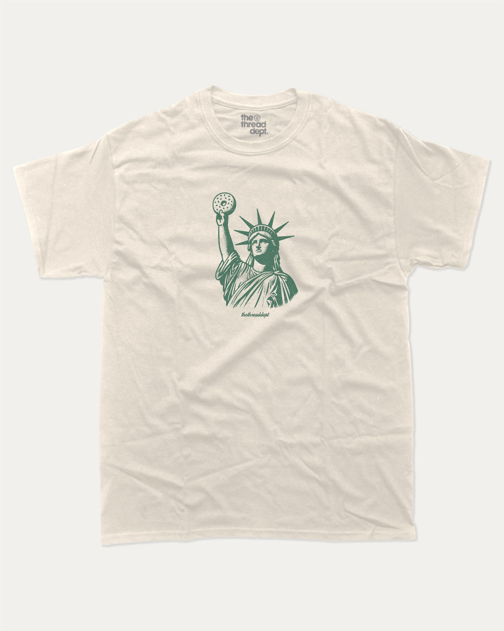 Statue of Liberty Bagle graphic tee with bold and humorous print, funny new york city graphic. Perfect for adults and gift-giving. Cream shirt.