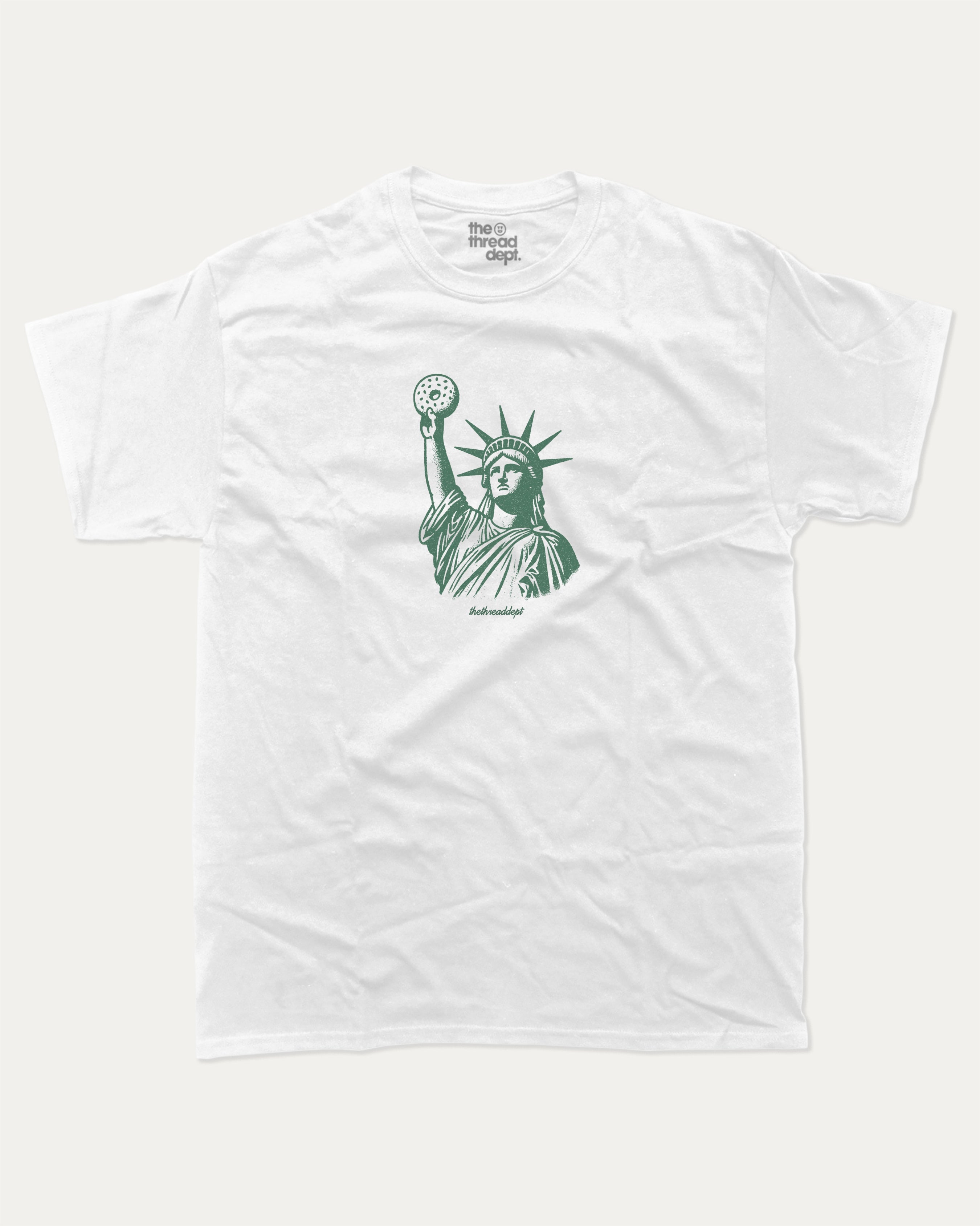 Statue of Liberty Bagle graphic tee with bold and humorous print, funny new york city graphic. Perfect for adults and gift-giving. White shirt.