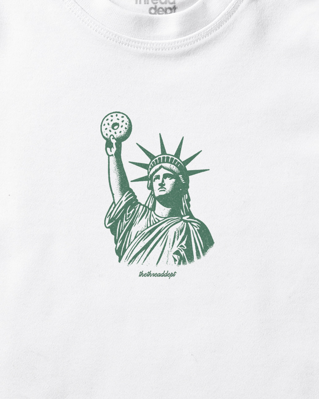White t-shirt with green Statue of Liberty Bagle graphic on a white background