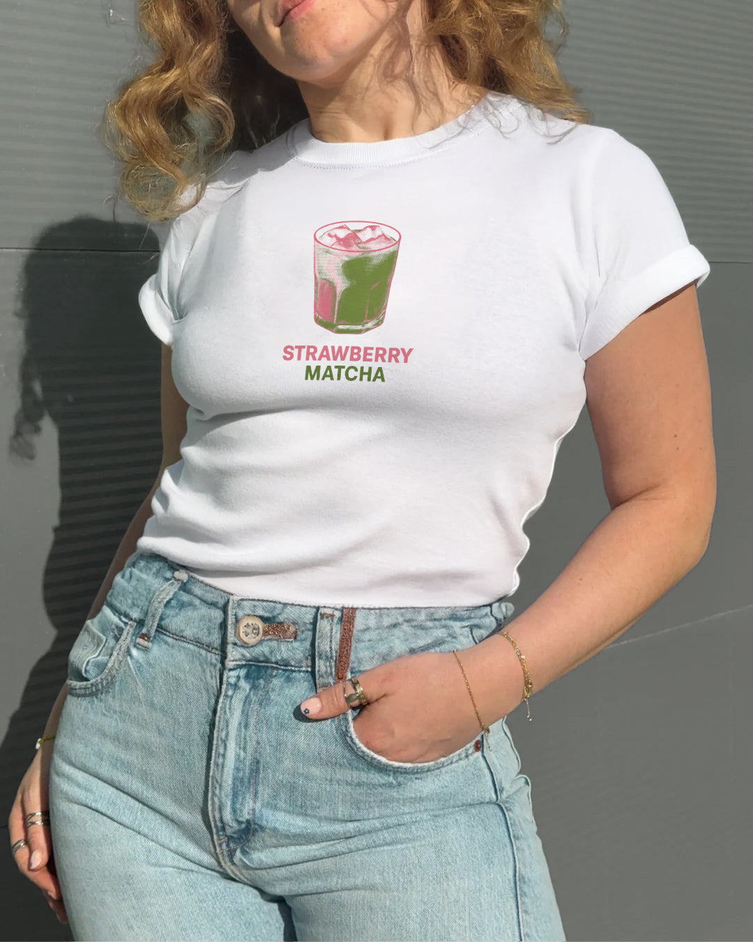 Person wearing a white t-shirt with a retro 'strawberry matcha' graphic design.