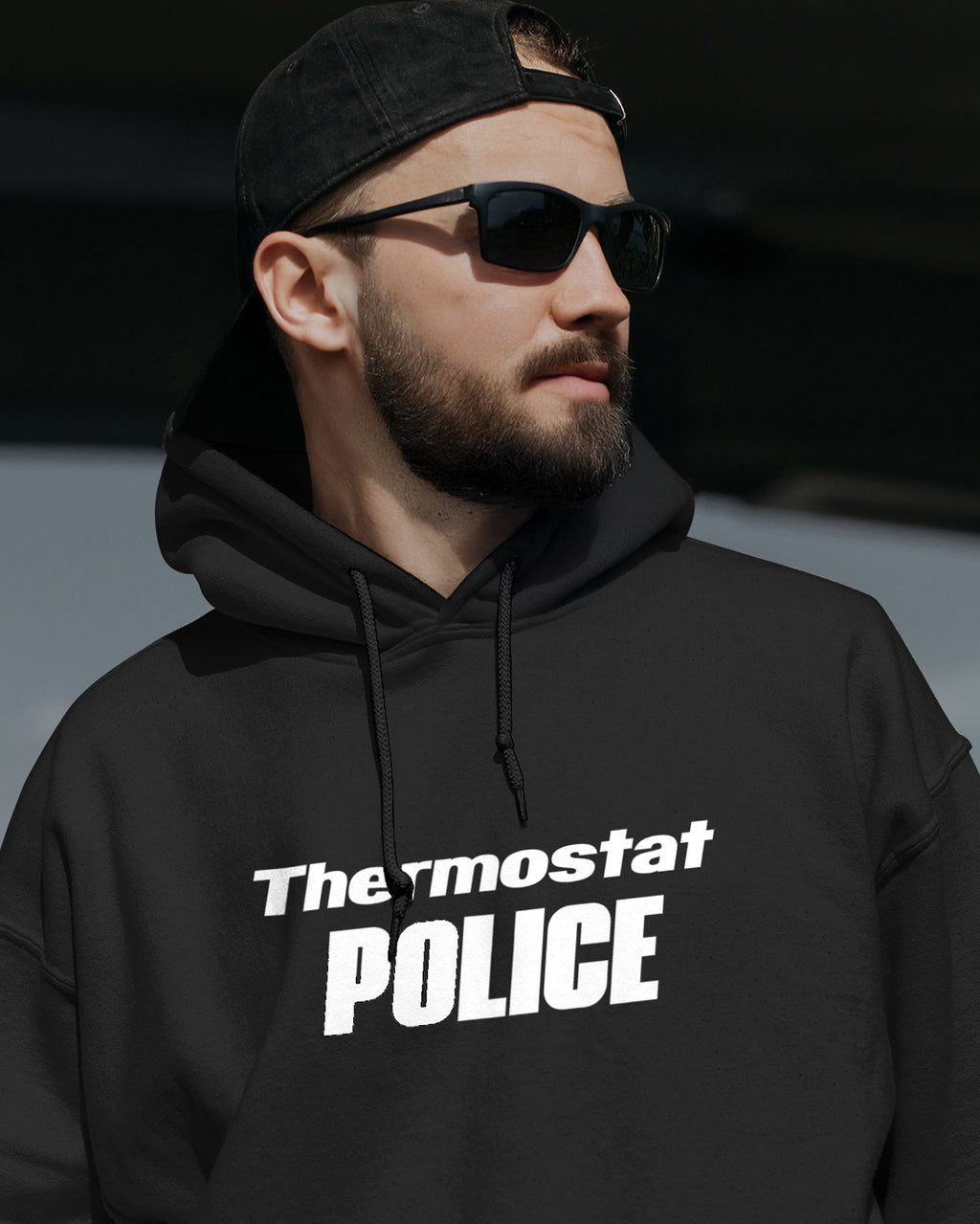 Man wearing a black hoodie with 'Thermostat POLICE' text, black cap, and sunglasses.
