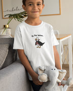 Child wearing a white t-shirt with a graphic design, sitting on a couch holding a stuffed elephant toy.