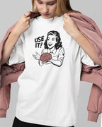 Person wearing a white t-shirt with a graphic design and text 'USE IT!' on a plain background